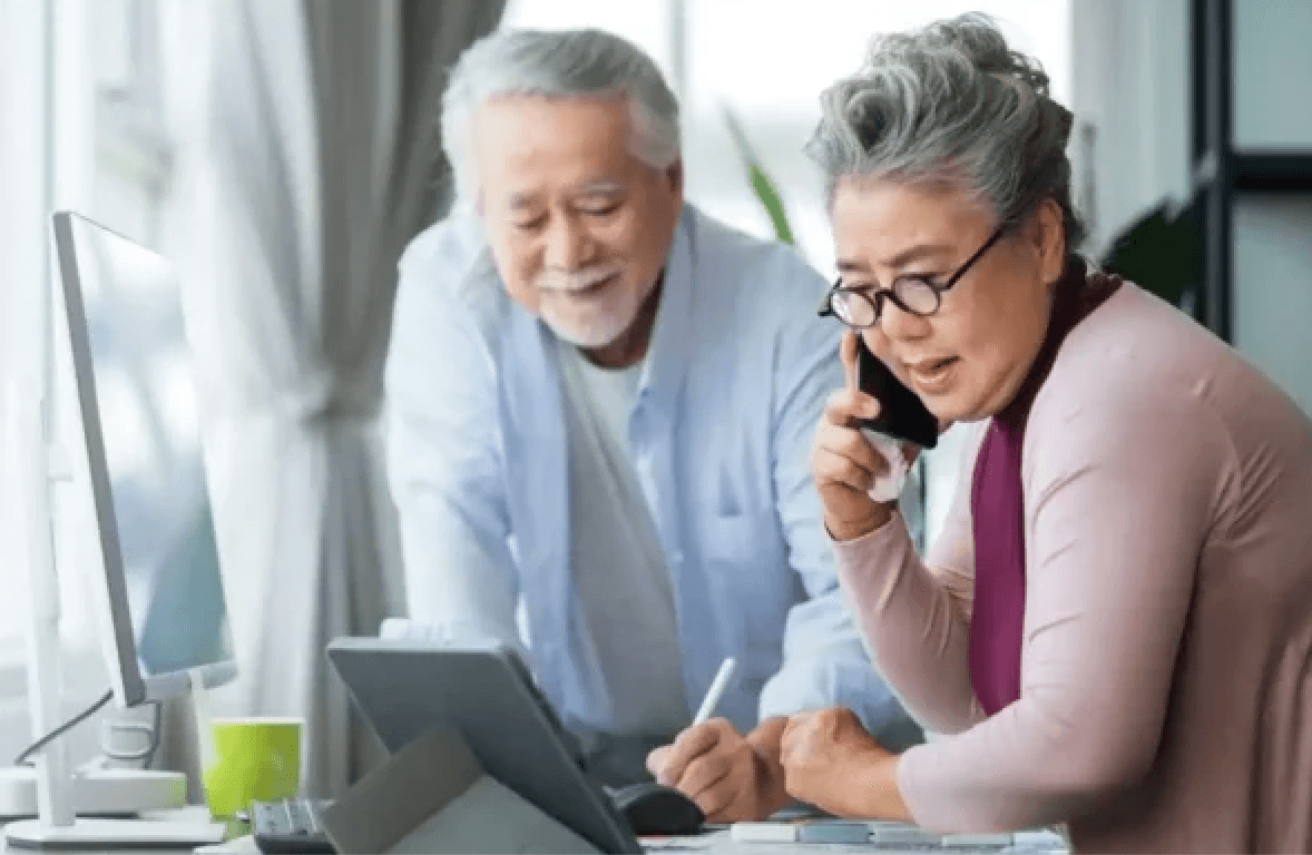 man and woman talking the phone. man is writing something down while woman looks at ipad.