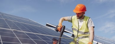 Worker installing solar panel on a rooftop